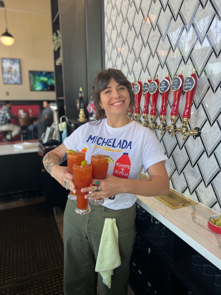 South of Shaw team member holding three micheladas at the bar.